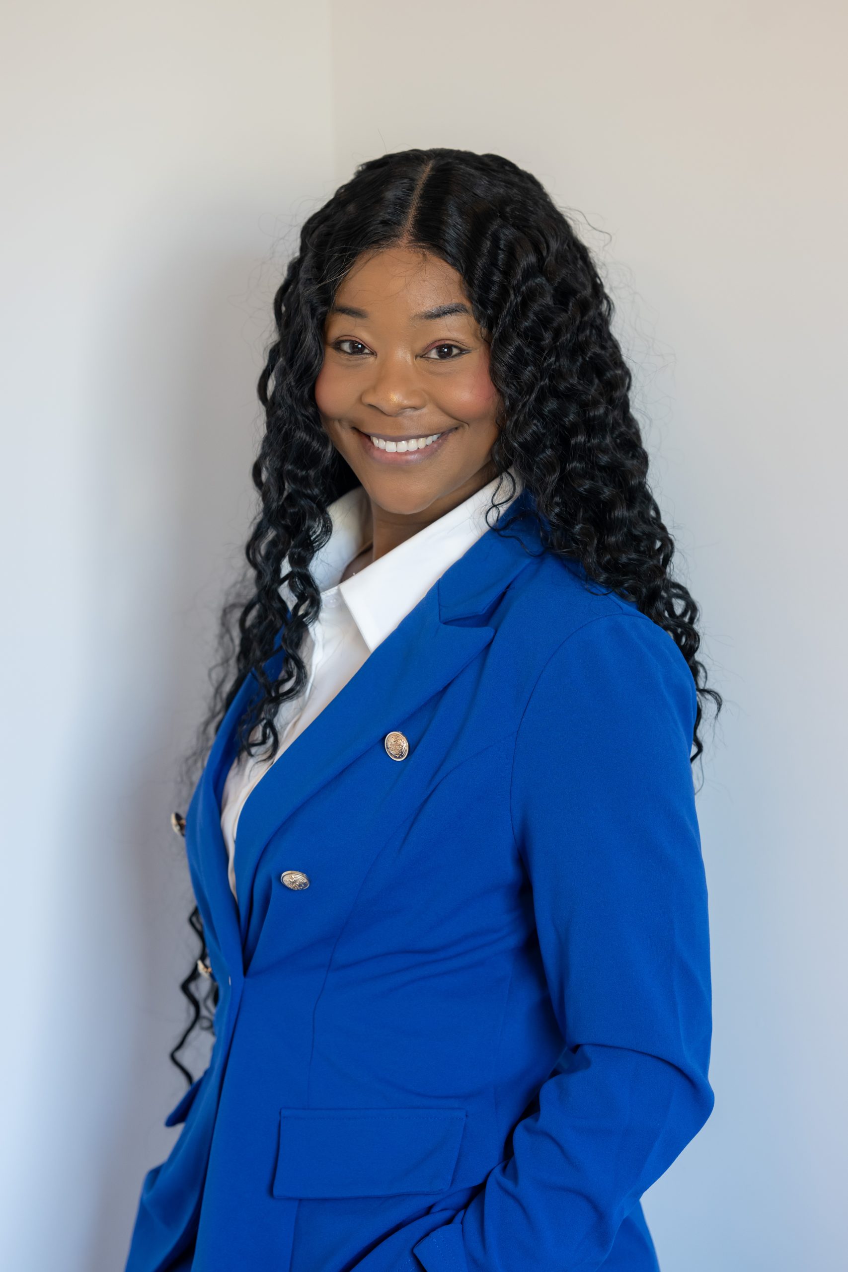 Mica Profile Photo 2 Profile photo of Michaelle "Mica" Julien wearing a blue suit jack on a soft-white background