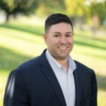 A profile photo of Mike DelRose Jr. with a landscaped green background