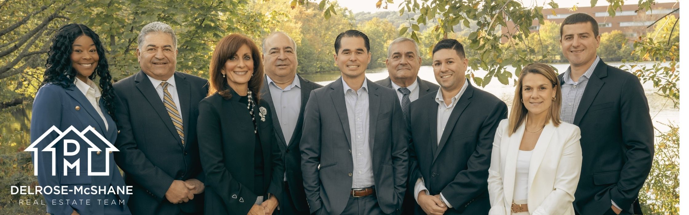 A photo of the DelRose McShane Team posing in front of a pond with the team logo in the lower left-hand corner of the banner image