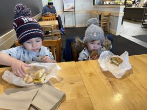 A photo of two young children sitting at a table and having bagels for breakfast at a local restaurant