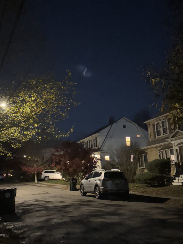 A photo of space debris traversing the sky in a spiral motion over the neighborhood